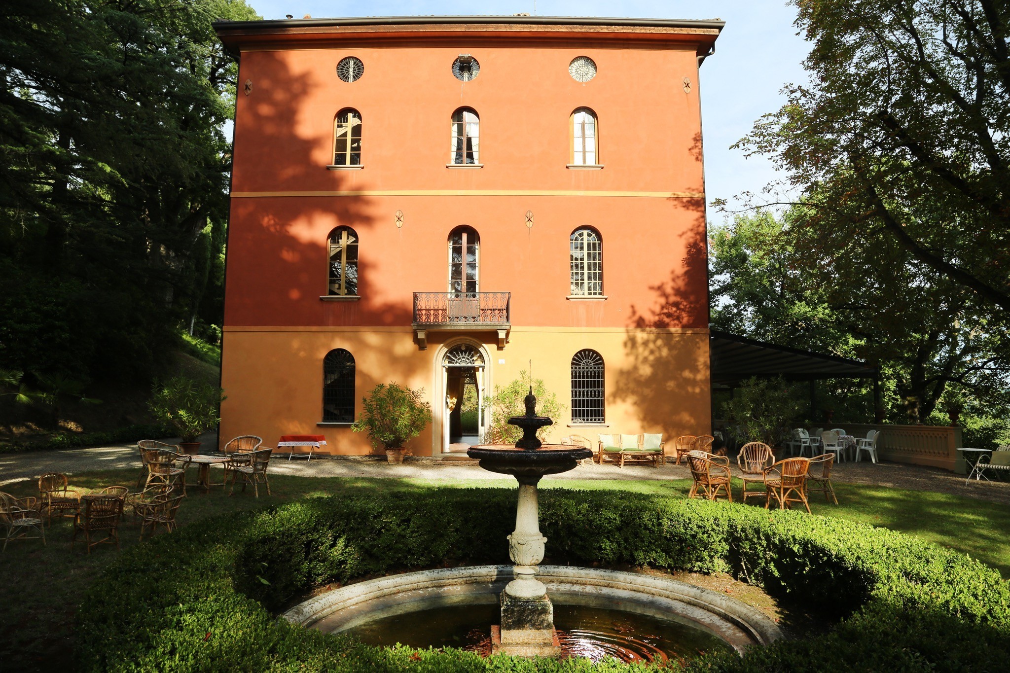 Villa Acquaderni — terracotta-orange historic villa facade with fountain and garden chairs in the Bologna hills